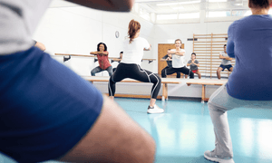 Sportlich gekleidete Menschen in einer Turnhalle.
