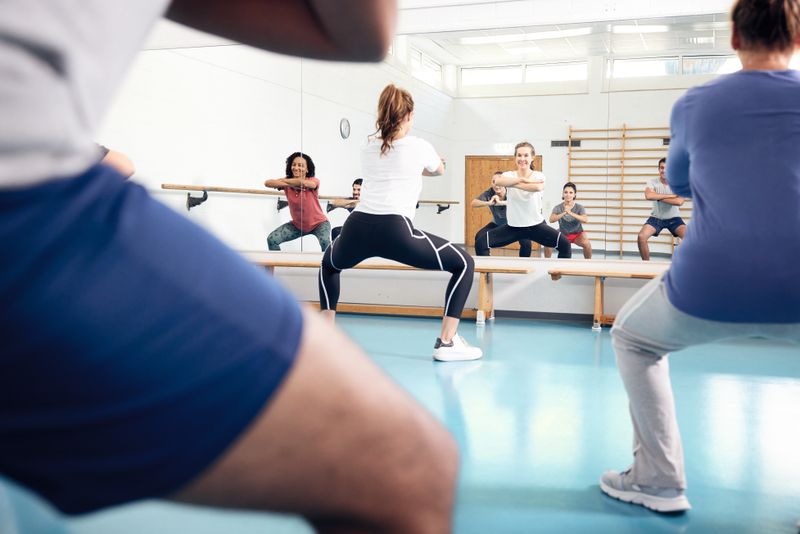 Sportlich gekleidete Menschen in einer Turnhalle.