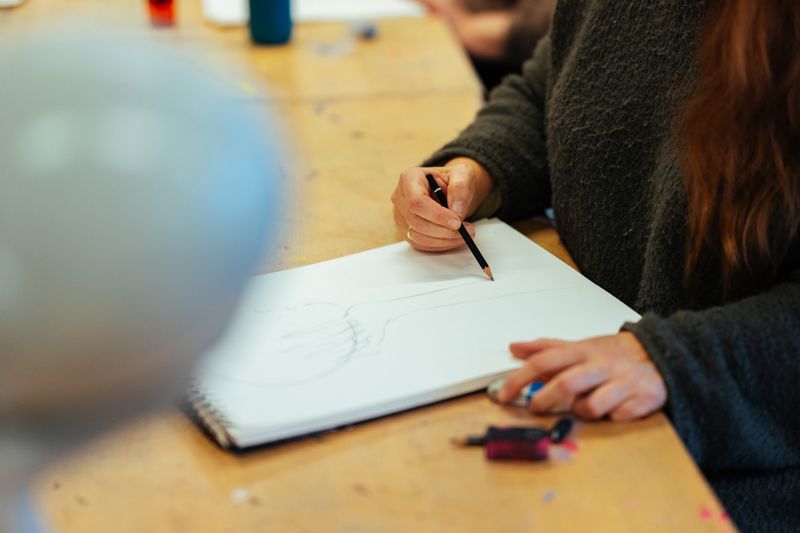 Die Hände einer Frau zeichnen auf einen Zeichenblock.
