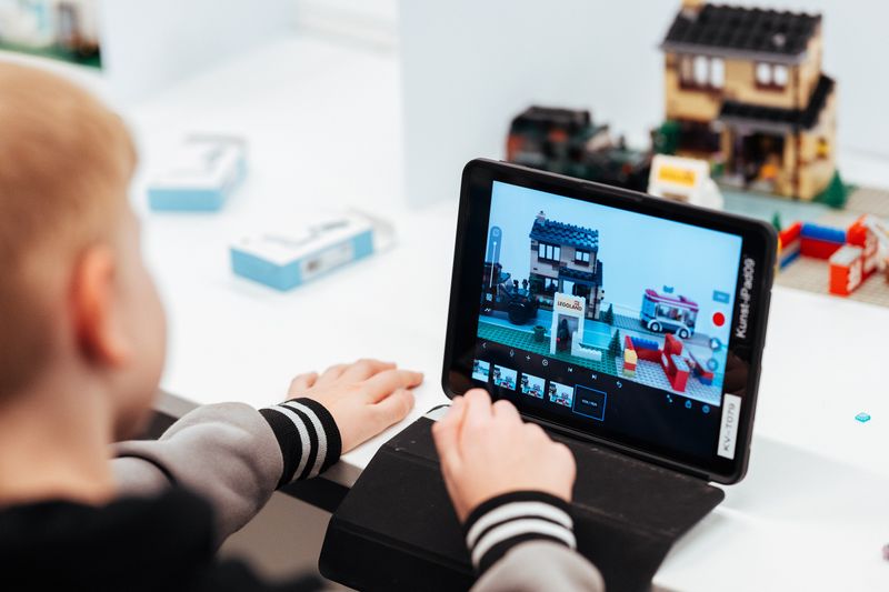Ein Junge guckt auf sein Tablet und bearbeitet einen Lego-Trickfilm