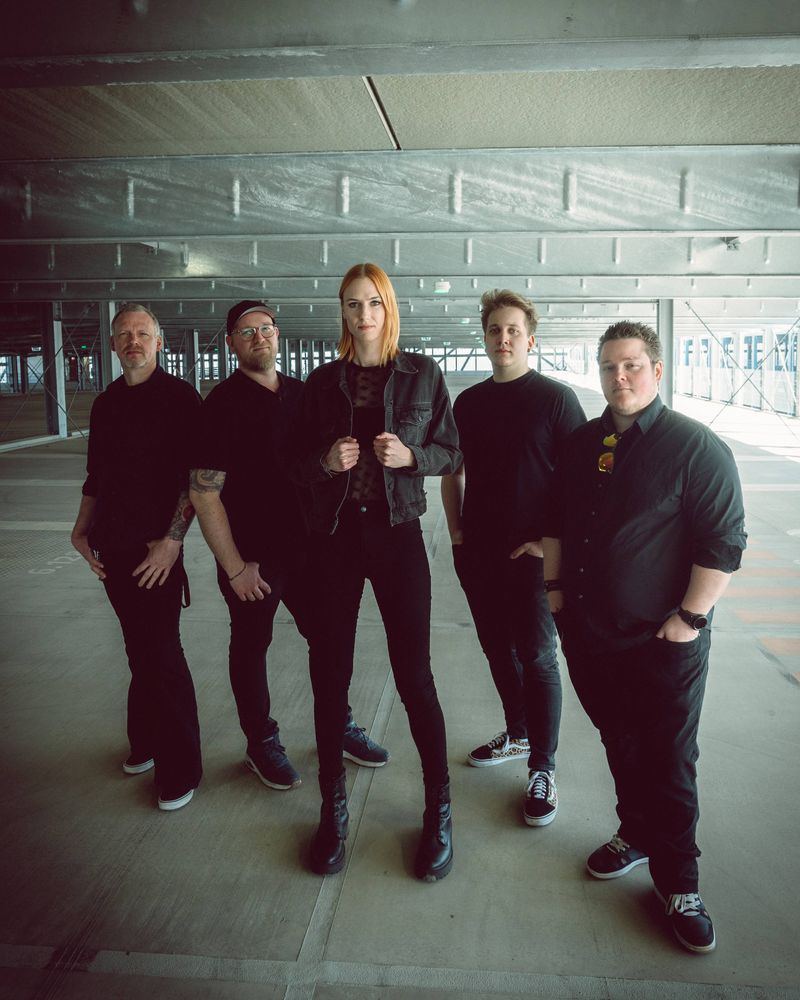 Fünf Bandmitlgieder stehen in einem Parkhaus nebeneinander.