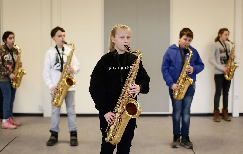 Blick auf fünf Kinder, die jeweils ein Saxophone in der Hand halten. 