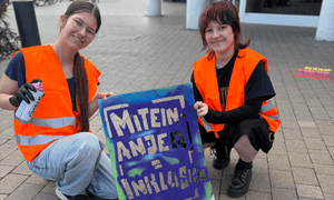 Zwei Mädchen halten eine Schablone und eine Sprühdose in der Hand. 