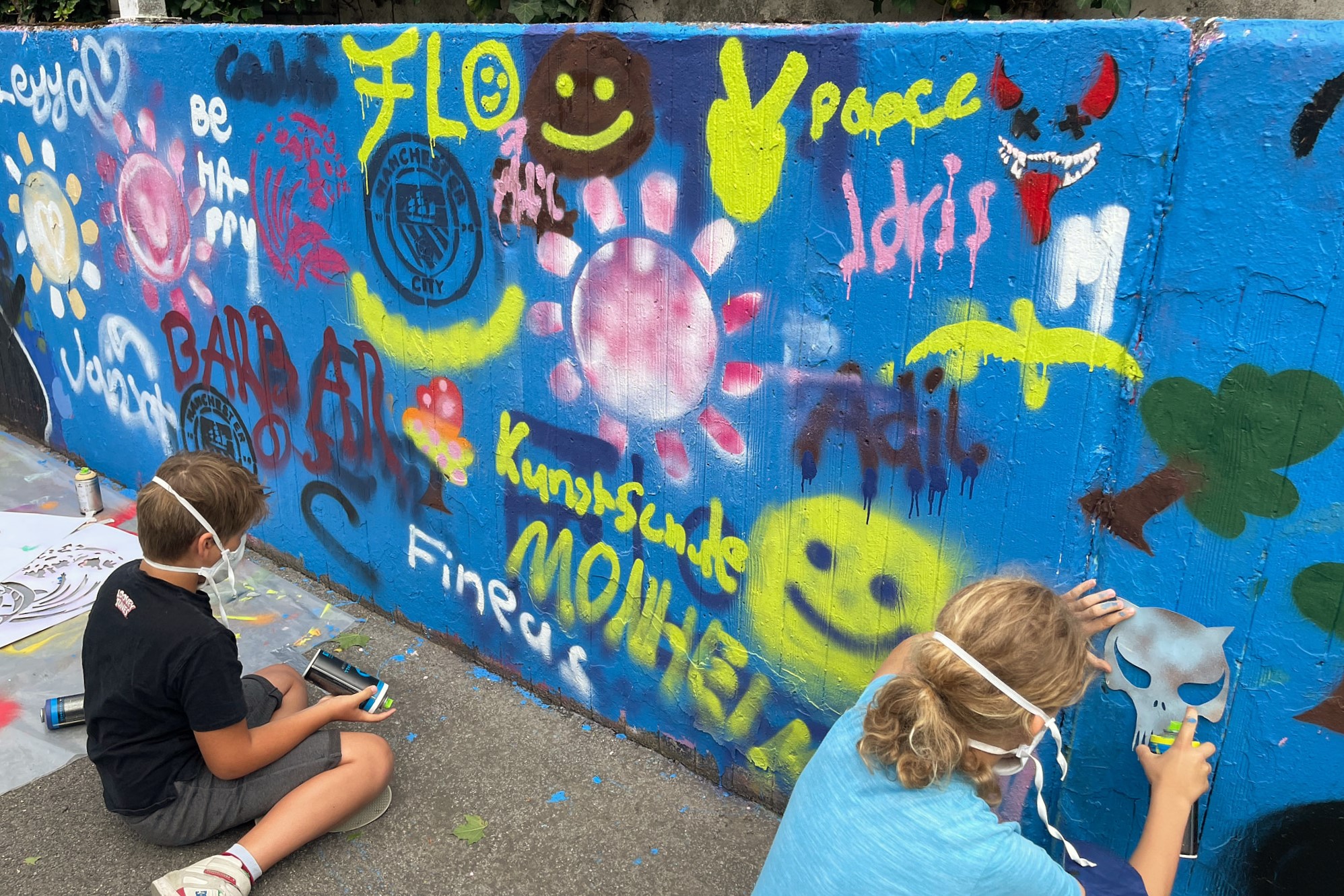 Zwei Personen vor einer bunt besprayten Wand.